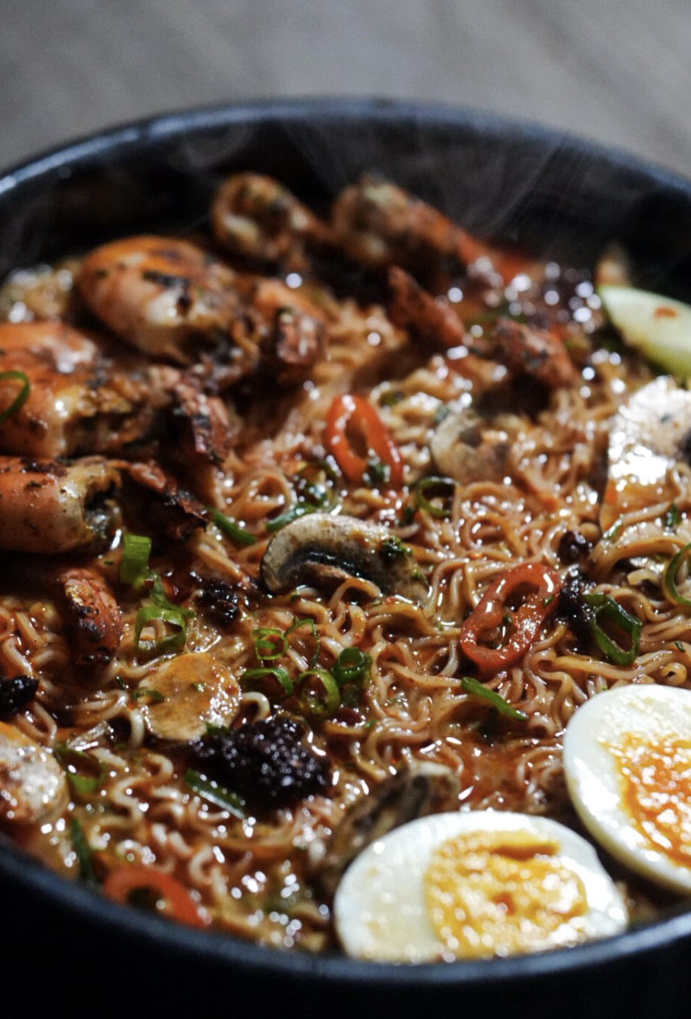 Seafood noodle bowl with shrimp, mushrooms, peppers, scallions, and jammy eggs