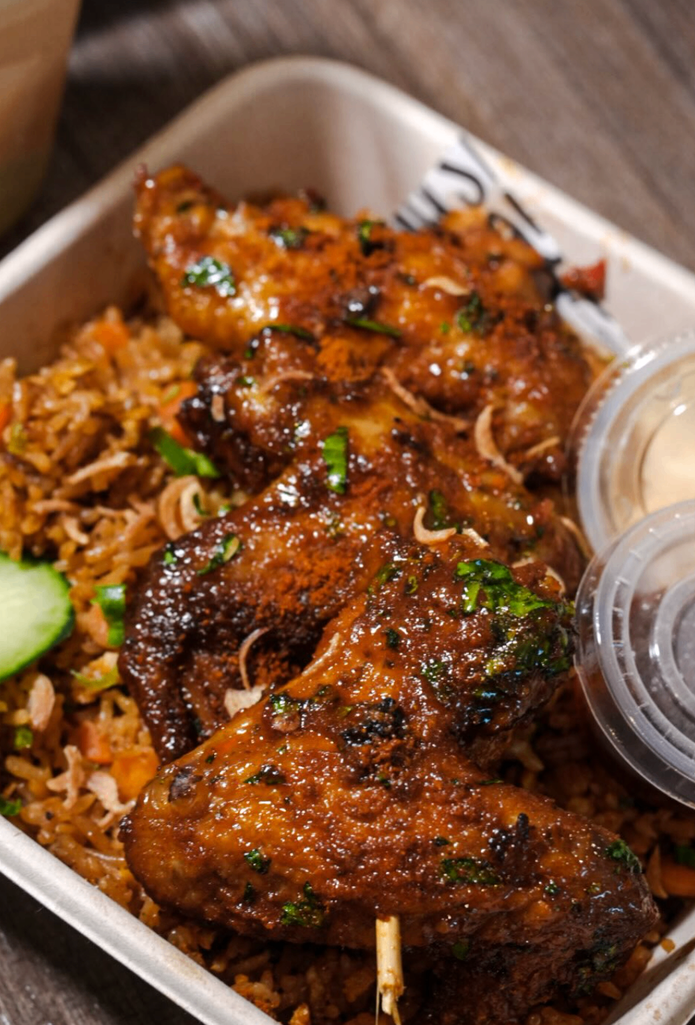 Spiced chicken wings served over seasoned rice with dipping sauces