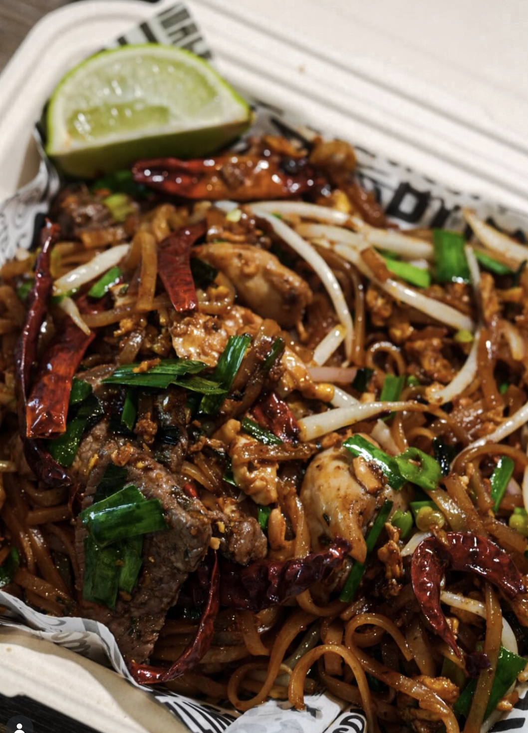 Stir-fried noodles with beef, bean sprouts, scallions, and lime