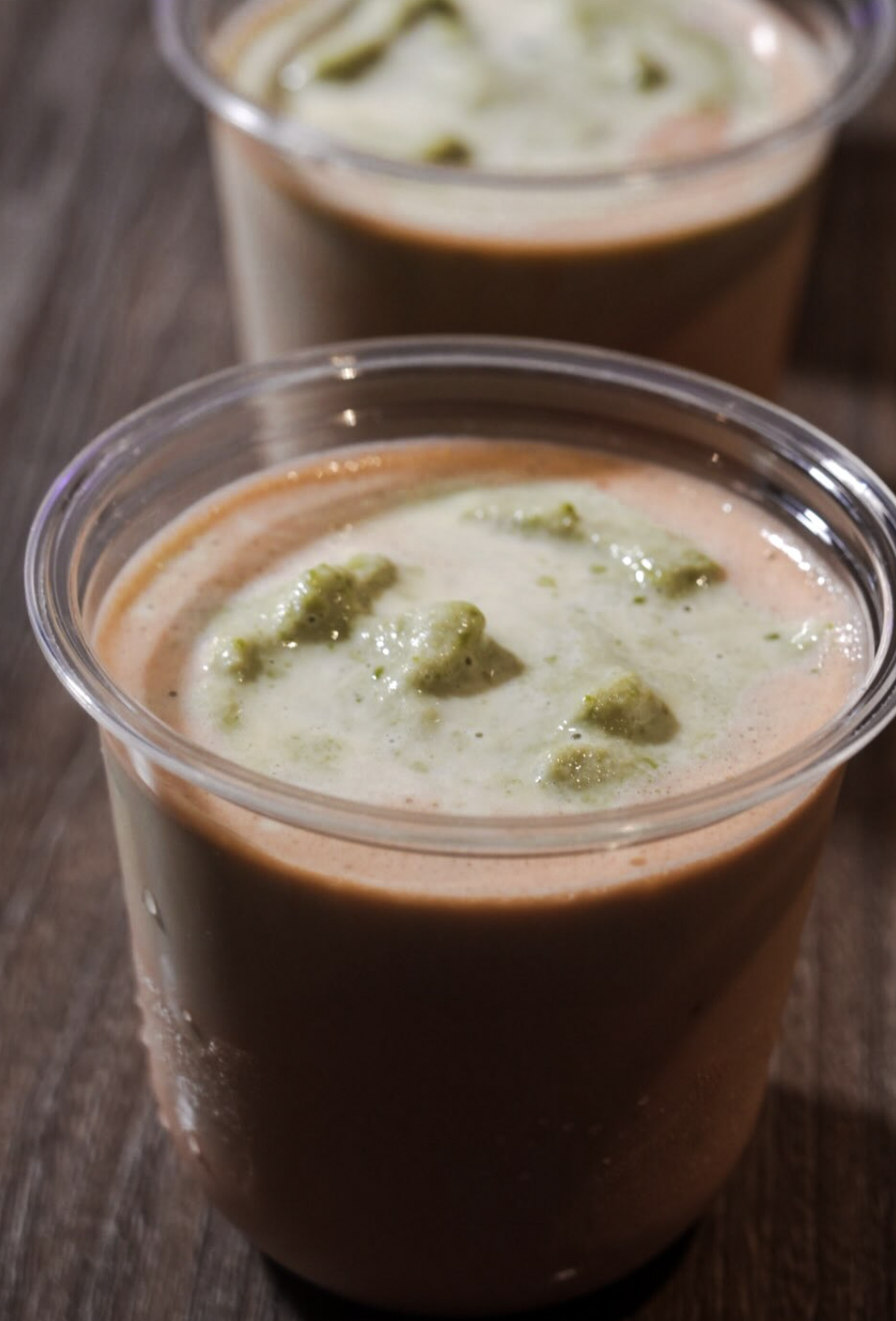 Two cups of rich wellness soup topped with a green herb garnish