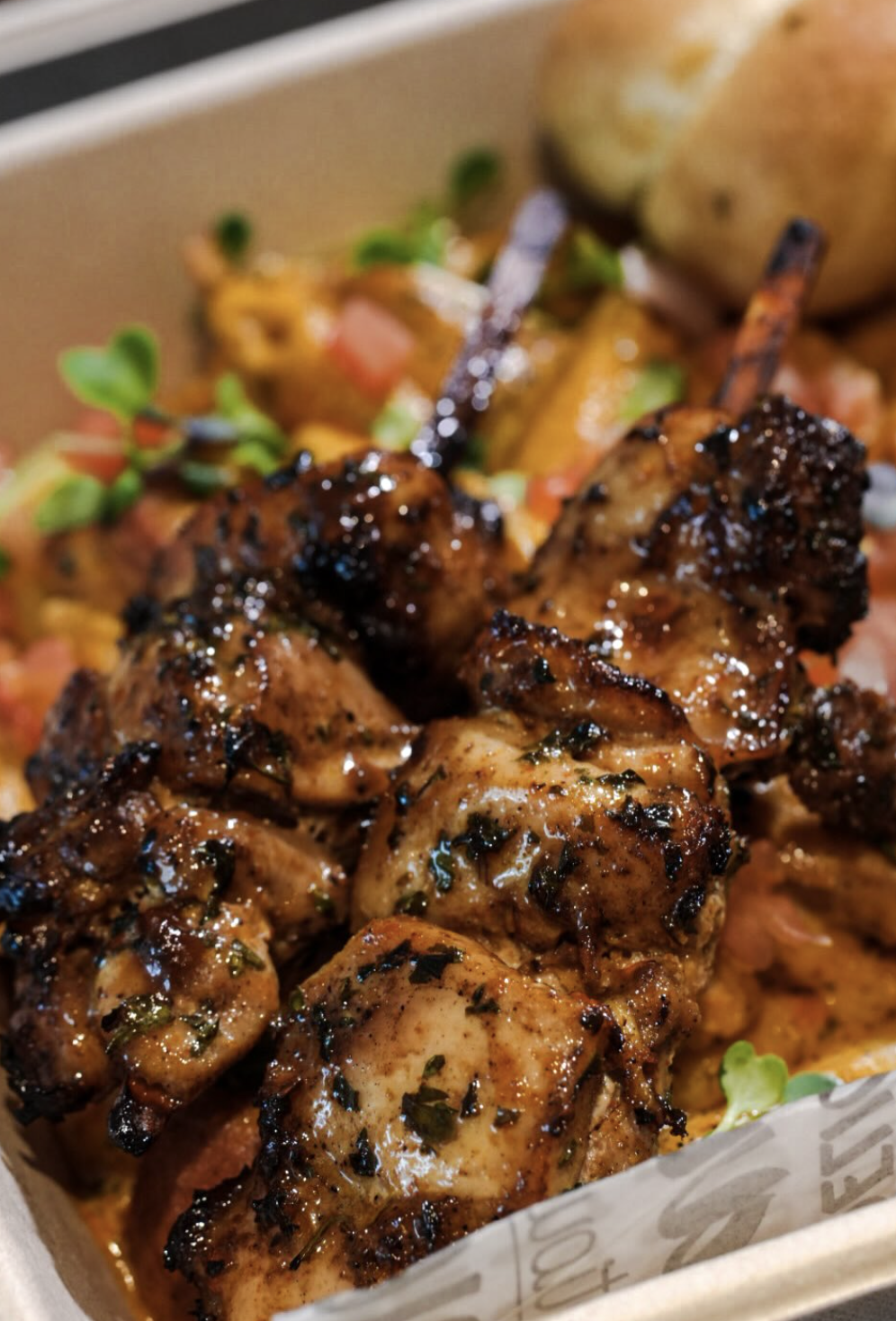 Glossy grilled chicken pieces served over sauced pasta