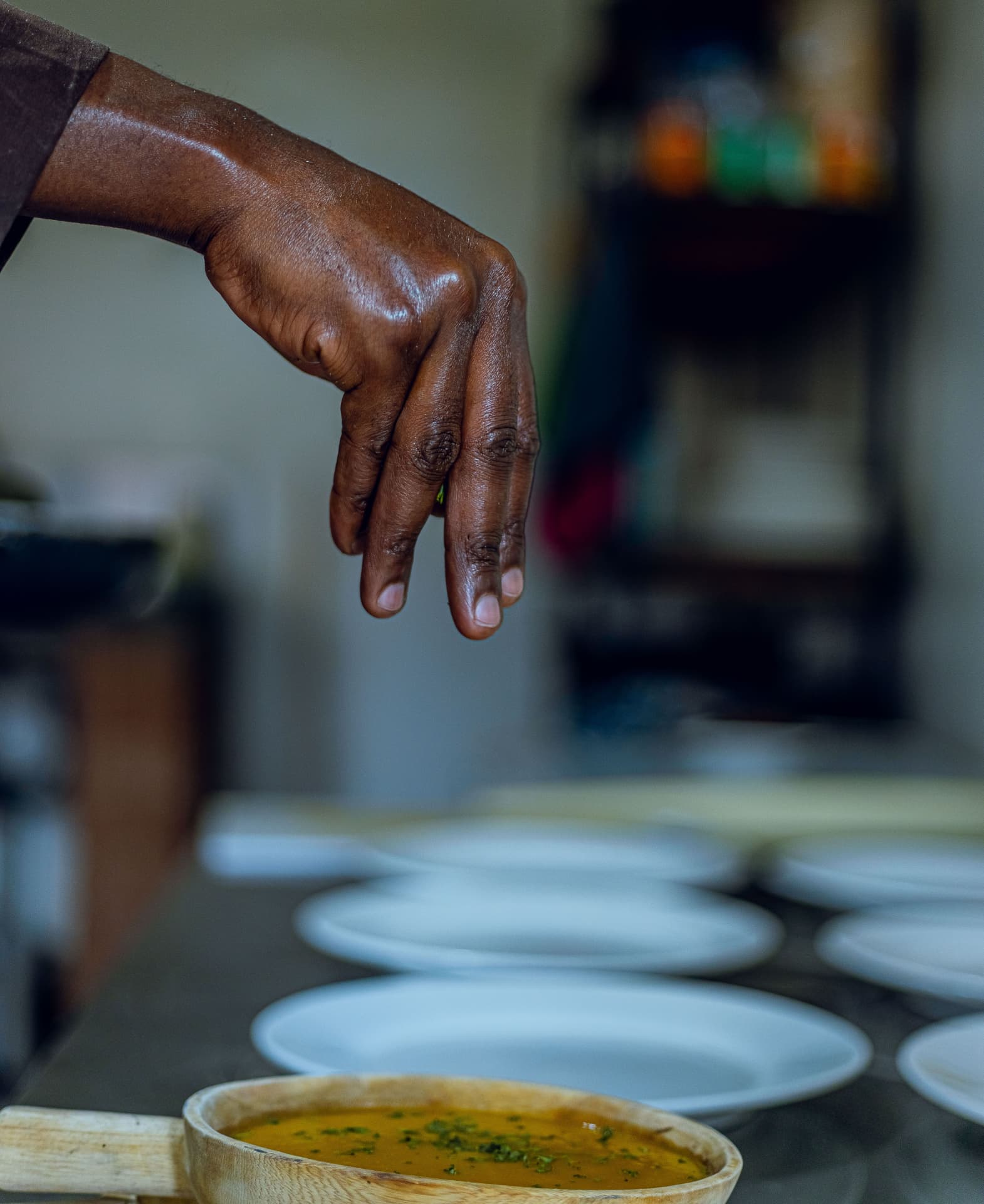 A cook's hand seasoning food in the kitchen