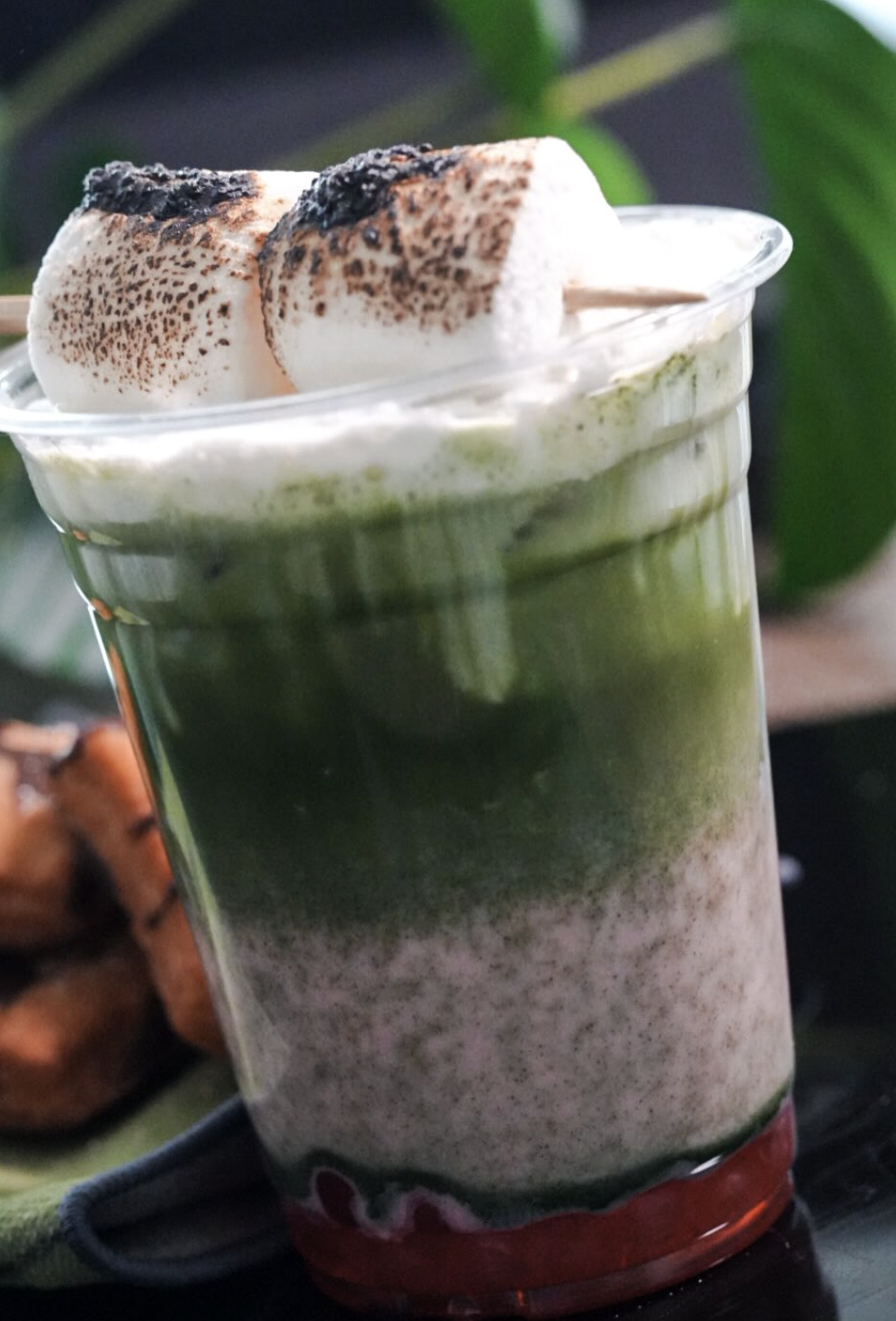 Close-up of a layered matcha latte with toasted marshmallows and berry syrup