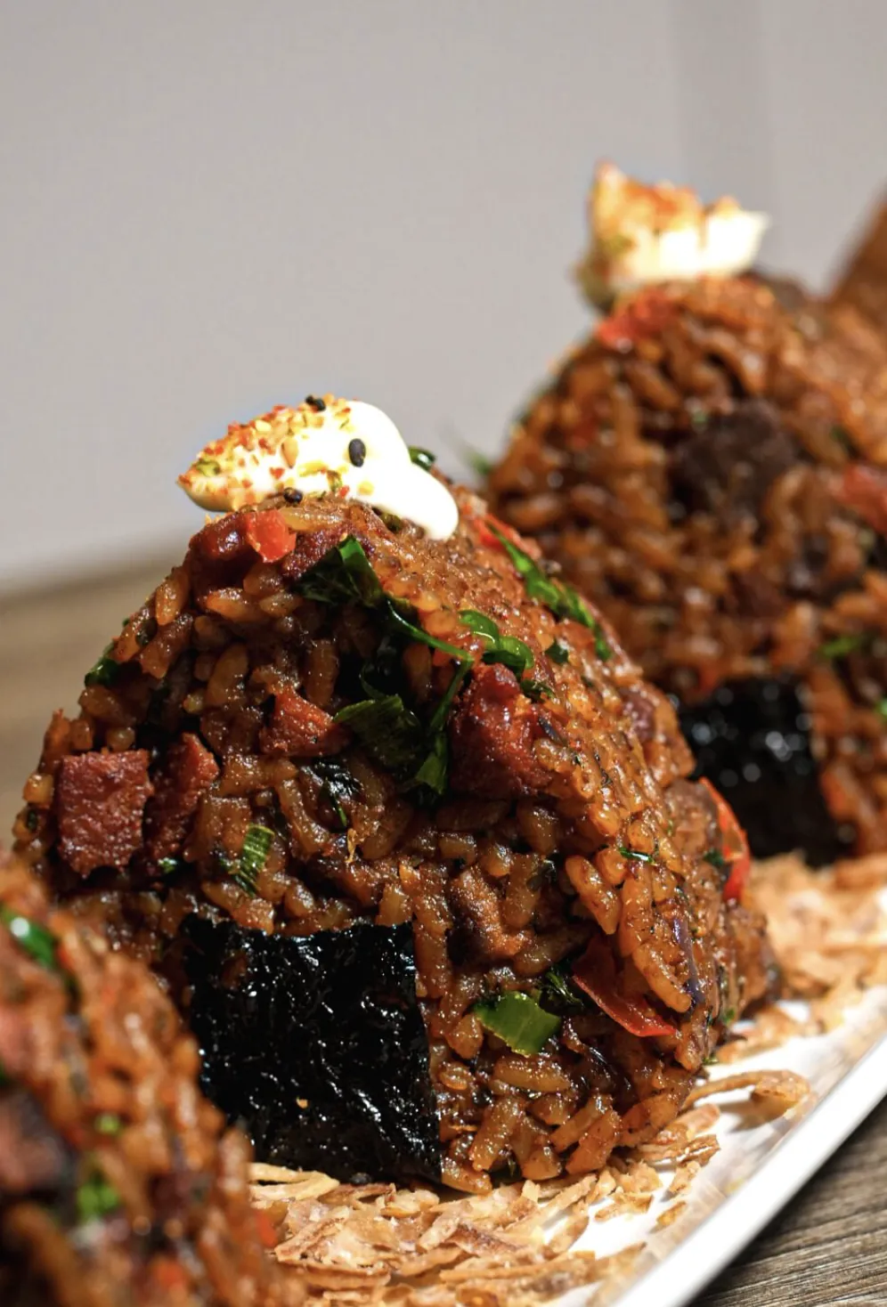 Lineup of molded jollof rice portions with beef, herbs, and cream garnish