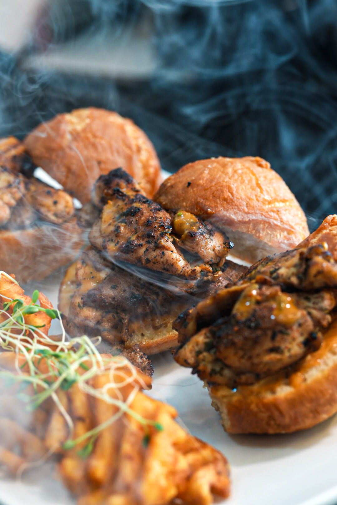 FloJoe's smoked chicken brioche sliders with waffle fries under drifting smoke