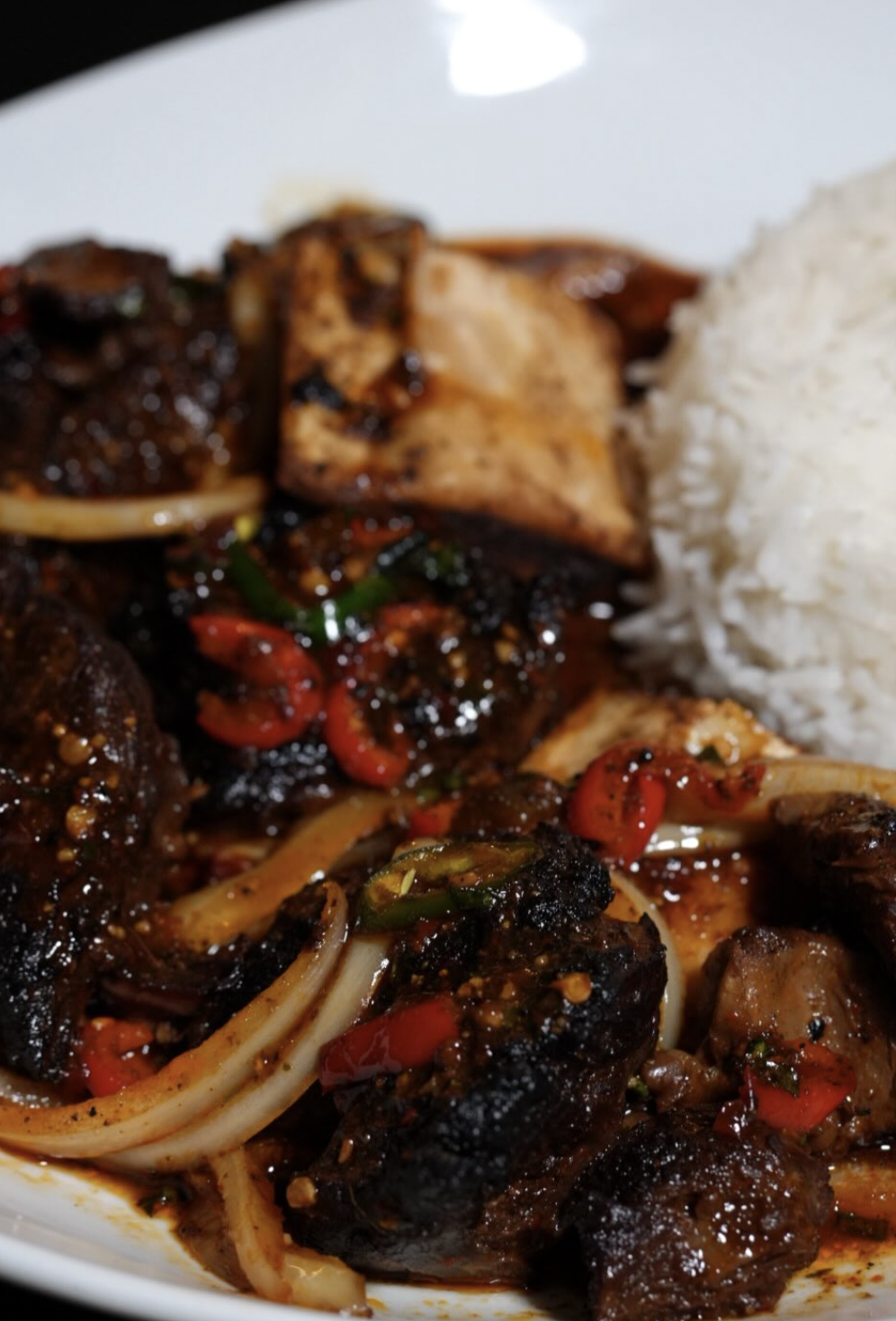 Close-up of braised beef and rice with peppers, onions, and charred edges